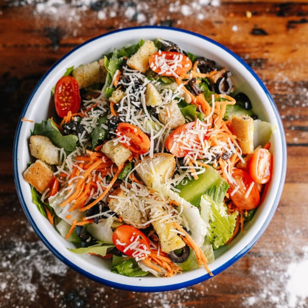 NY Pie's fresh garden salad with lettuce, tomatoes, olives, carrots, croutons, and shredded cheese.